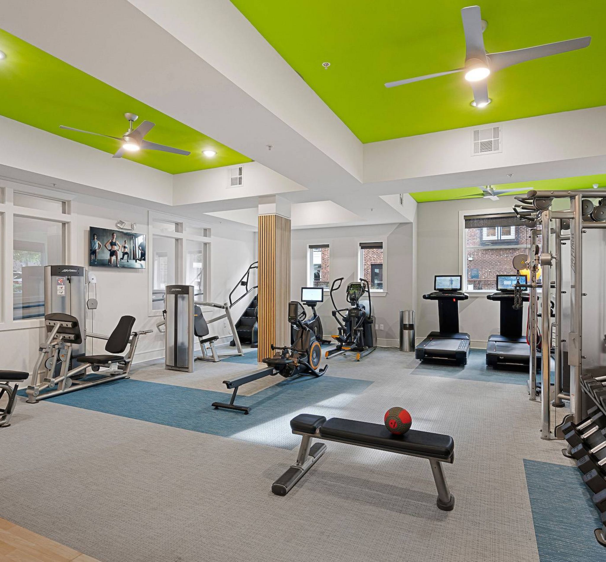 Large fitness center with lime green ceiling and plentiful equipment at 808 Hawthorne apartments